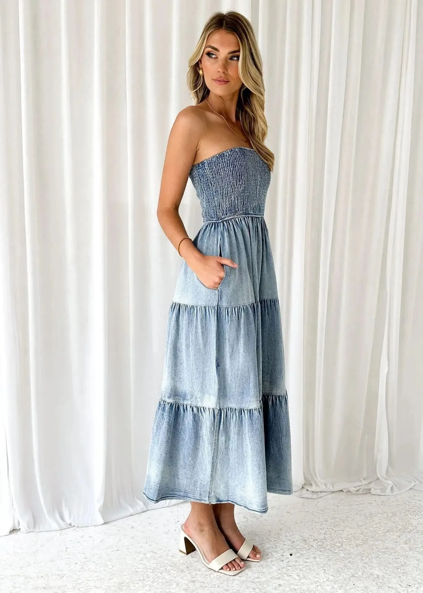 Denim strapless tiered maxi dress with a gathered bodice, side slit, and patchwork hem